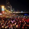 Turistas en la playa de Mazatlán durante el jueves Santo, con el malecón y el Olas Altas al fondo.