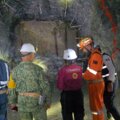 Brigadistas dentro de la mina Santa Fe instalando equipos de bombeo, iluminados por linternas y cascos.