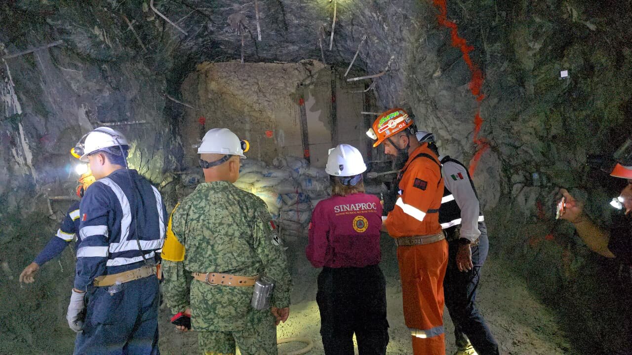 Brigadistas dentro de la mina Santa Fe instalando equipos de bombeo, iluminados por linternas y cascos. Brigadistas dentro de la mina Santa Fe instalando equipos de bombeo, iluminados por linternas y cascos.