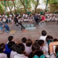 Estudiantes de la primaria STASE observan a un instructor en silla de ruedas activa subiendo una plataforma simulando una banqueta.